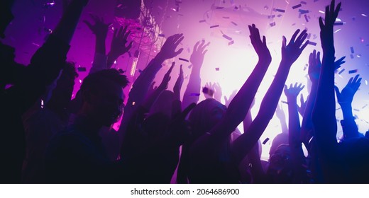 Photo of carefree millennials fans buddy enjoy famous rock star show dance raise hands up on neon discotheque flying confetti