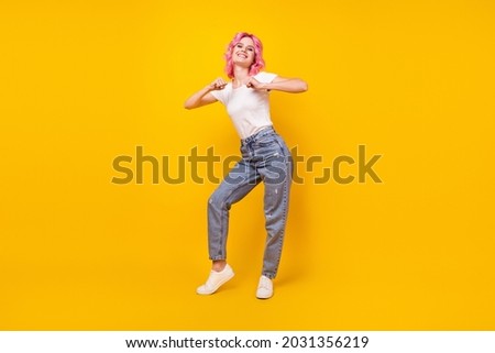 Photo of carefree shiny young woman dressed white t-shirt smiling walking dancing isolated yellow color background