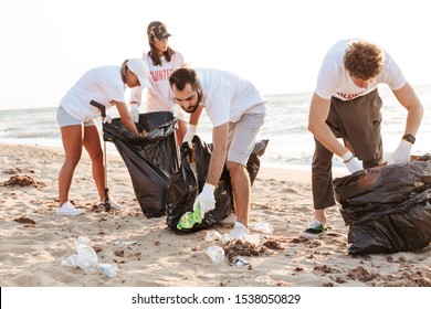 Photo of caucasian eco volunteers people cleaning beach from plastic with trash bags at seaside - Powered by Shutterstock