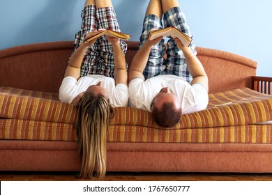 Photo of Caucasian young couple lying on the bed and reading book.Young people are spending time together.Couple dressed in pajamas lying in the bed and reading book.Smart couple reading book together