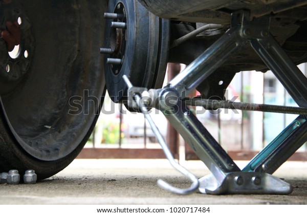Photo for changing the spare tire in home garage\
with the jack supporting the\
car.
