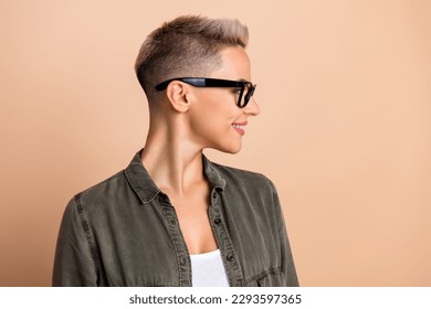 Photo of charming adorable lady dressed khaki shirt eyewear looking emtpy space isolated beige color background
