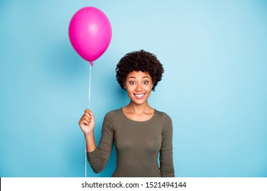 Photo of charming cheerful cute sweet pretty childish black woman holding air ball with hands smiling toothily with excited facial expression isolated over blue vibrant color background