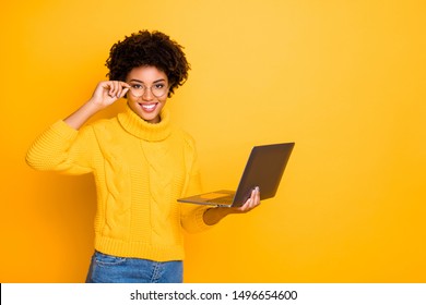 Photo of charming cute black curly attractive girlfriend holding her laptop and spectacles searching for something getting likes wearing jeans denim yellow pullover isolated vivid color background