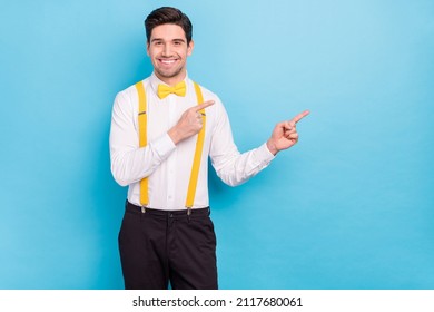 Photo of charming cute guy wear yellow suspenders white shirt pointing empty space isolated blue color background