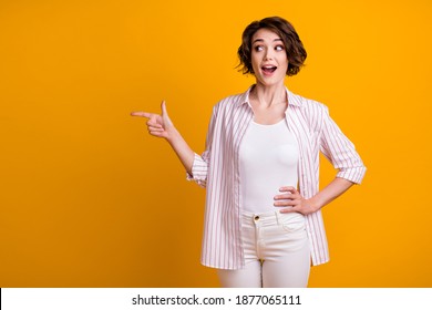 Photo Of Charming Excited Young Girl Hand Hip Point Finger Look Empty Space Advising Better Option Object Open Mouth Wear White Striped Shirt Isolated Yellow Bright Color Background