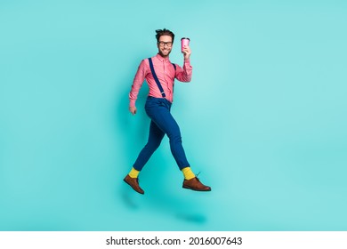 Photo of charming funny young gentleman wear pink shirt glasses drinking coffee running smiling isolated teal color background