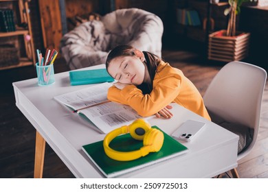 Photo of charming little girl do homework sleeping tired sit table dressed orange garment spend pastime spacious house indoors room - Powered by Shutterstock