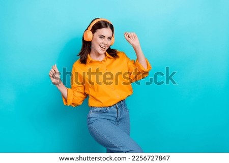 Photo of charming lucky lady wear orange shirt listening songs earphones having fun isolated turquoise color background