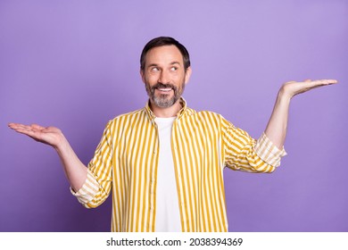 Photo of charming mature happy man look hold hands empty space compare scales isolated on purple color background