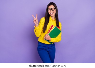 Photo of charming nice pretty young woman make v-sign smile hold hands notebooks isolated on purple color background