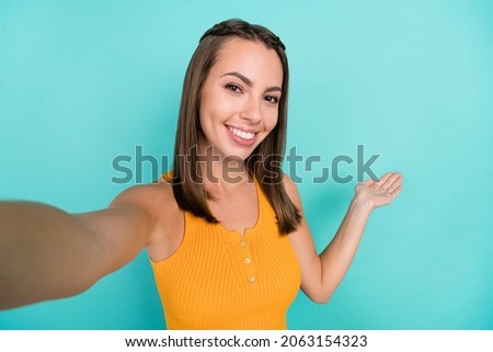 Photo of charming positive happy woman make selfie invite you hand empty space isolated on teal color background