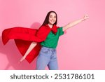 Photo of charming positive woman wear green t-shirt superhero cape rising fist empty space isolated pink color background