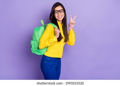 Photo of charming pretty lovely young woman make v-sign wear rucksack isolated on purple color background