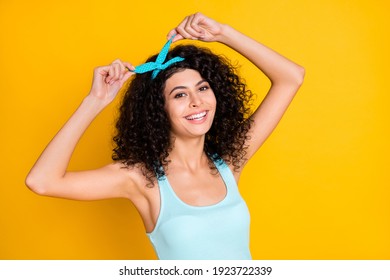 Photo of charming shiny curly woman wear teal singlet smiling adjusting hair band isolated yellow color background - Powered by Shutterstock