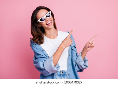 Photo Of Charming Shiny Lady Dressed Jeans Clothes Dark Eyewear Pointing Two Fingers Empty Space Isolated Pink Color Background