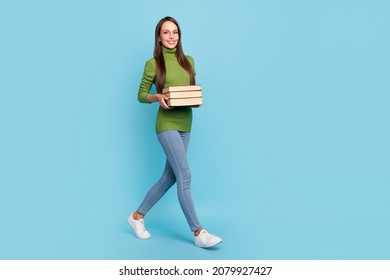 Photo of charming smart young woman wear green turtleneck glasses smiling walking holding book stack isolated blue color background