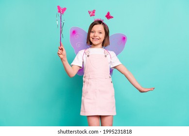 Photo of charming sweet schoolgirl dressed pink overall eyewear wings holding fairy wand isolated turquoise color background