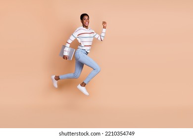 Photo Of Charming Sweet Unisex Person Wear Sweater Running Jumping Holding Device Isolated Beige Color Background