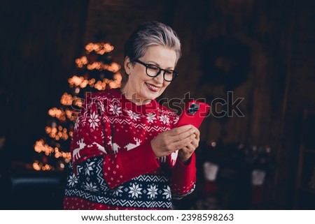 Photo of charming sweet woman wear red print xmas sweater typing apple iphone samsung christmas greetings indoors apartment room