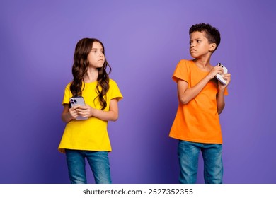 Photo of charming two little children annoyed look each other hide device wear trendy orange yellow outfit isolated on violet background - Powered by Shutterstock