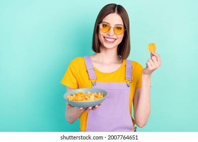 Photo of charming young happy positive woman hold hands plate potato chips isolated on teal color background