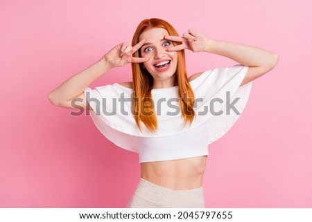 Photo of charming young woman make fingers v-signs eyes funky mood isolated on pastel pink color background