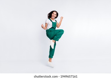 Photo of cheerful astonished lady raise fists open mouth wear green overall sneakers isolated white color background - Shutterstock ID 1949657161