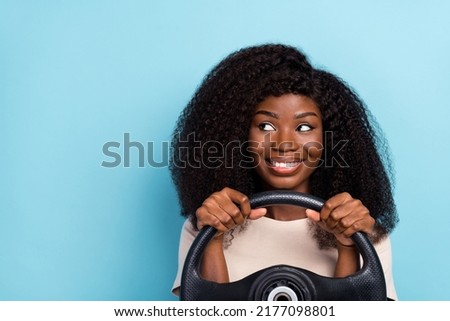 Photo of cheerful attractive girl arms hold wheel look interested empty space isolated on blue color background