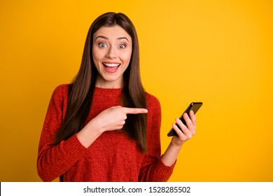 Photo of cheerful attractive overjoyed cute trendy youngster pointing at her telephone expressing amazement with face wearing red sweater isolated over vivid color background - Powered by Shutterstock