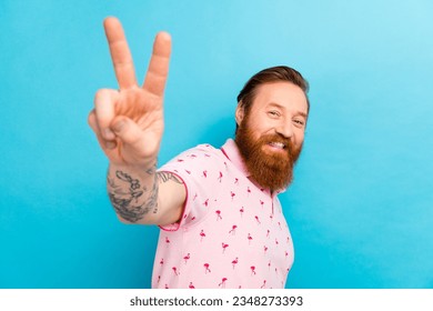 Photo of cheerful attractive person beaming smile arm fingers demonstrate v-sign isolated on blue color background