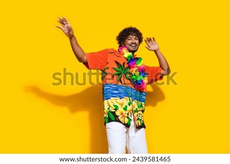Photo of cheerful carefree man dressed print shirt flower necklace dancing at party hands up isolated on vivid yellow color background