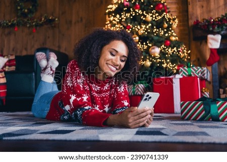 Photo of cheerful cute girl lying on floor carpet reading congratulations iphone rejoicing christmas day in decorated room indoors