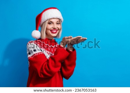 Photo of cheerful cute woman lady santa elf wear ornament pullover holding two arms empty space isolated blue color background