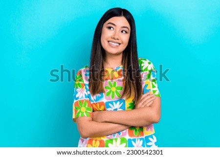 Photo of cheerful dreamy lady wear flower print t-shirt arms folded looking empty space isolated blue color background