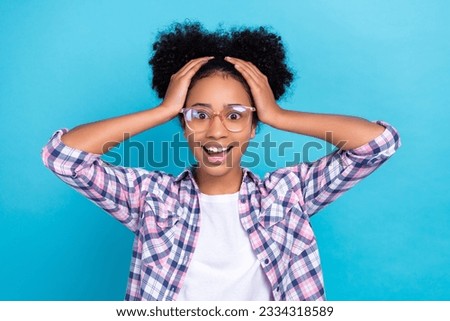 Photo of cheerful excited girl dressed checkered shirt eyewear arms head isolated blue color background