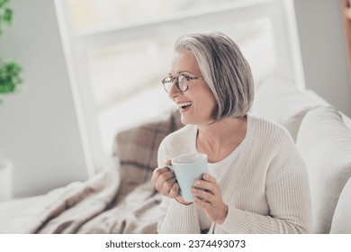 Photo of cheerful excited senior lady dressed white cardigan drinking cacao watching tv indoors house room - Powered by Shutterstock