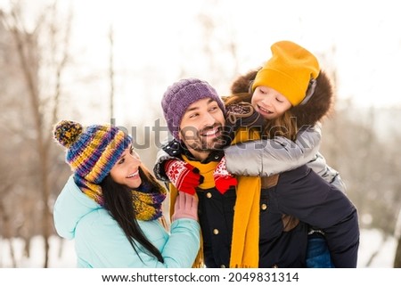Photo of cheerful family mommy daddy daughter piggyback happy positive smile look each other winter trip outdoors