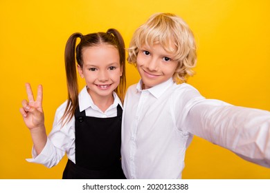 Photo of cheerful friendly classmate kids take selfie show v-sign wear school uniform isolated yellow color background