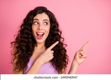 Photo of cheerful funky funny crazy nice glad sweet attractive girl pointing at emptiness away from her surprisingly while isolated with pink background