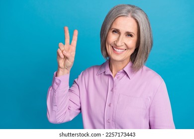 Photo of cheerful good mood satisfied office manager company owner old business worker show v-sign victory symbol isolated on blue color background