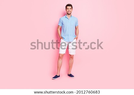 Photo of cheerful handsome confident guy hands pockets wear blue shirt shorts footwear isolated on pink color background