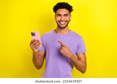 Photo of cheerful handsome funny person direct finger arm hold smart phone isolated on yellow color background - Shutterstock ID 2314619357