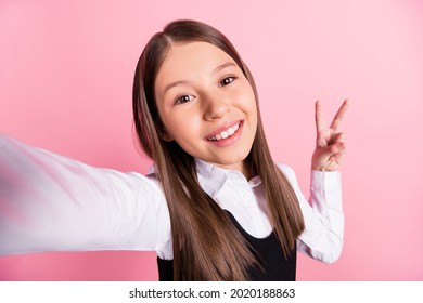 Photo of cheerful happy positive young small girl good mood v-sign make selfie isolated on pink color background