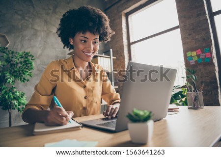 Photo of cheerful joyful mixed-race woman in yellow shirt smiling toothily writing down notes holding training for students to be executives at laptop desktop table Foto d'archivio © 