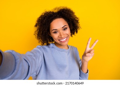 Photo of cheerful lady make selfie arm fingers demonstrate v-sign toothy smile isolated on yellow color background