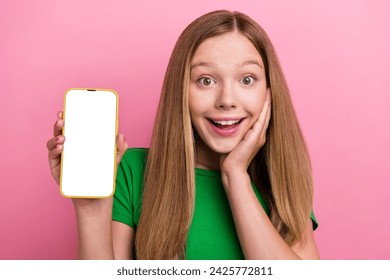 Photo of cheerful lovely excited girl wear green trendy clothes showing modern device empty space isolated on pink color background