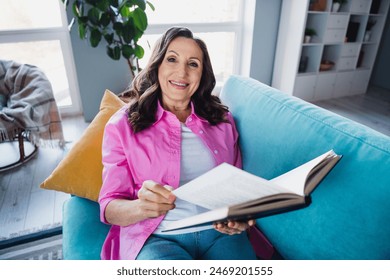 Photo of cheerful lovely nice senior woman sitting sofa reading book story comfy room indoors - Powered by Shutterstock