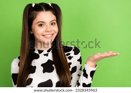 Photo of cheerful lovely person beaming smile hand palm hold demonstrate empty space isolated on green color background