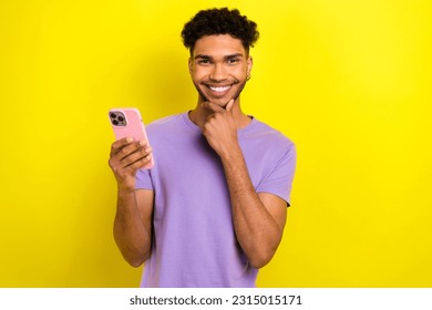 Photo of cheerful minded creative person hand touch chin toothy smile hold smart phone isolated on yellow color background - Shutterstock ID 2315015171